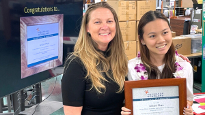 2 woman, 1 holding a framed certificate