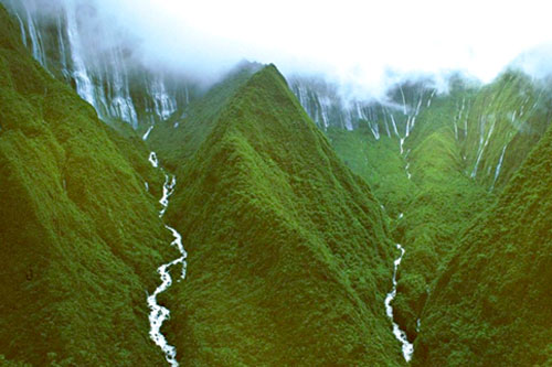 Koolau mountain range catching heavy raining clouds at the top ridges causing many waterfalls to pour down its sides collecting into rivers of of fresh water